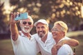 Friends memories. Senior golfers using phone and taking self portrait. Focus is on background Royalty Free Stock Photo