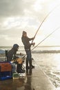 Friends, men and fishing on pier at beach with rod, water and relax on vacation, holiday and travel. Friendship, people Royalty Free Stock Photo