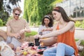 Two girls and guy opening drink at picnic Royalty Free Stock Photo