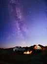 Friends near Bonfire, Pickup Truck, Tent and Bike in the Mountains under Night Sky with Milky Way. Adventure and Travel Royalty Free Stock Photo