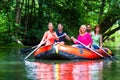 Friends paddling on rubber boat at forest river or creek