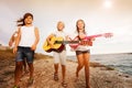 Friends playing guitar while walking on the beach Royalty Free Stock Photo