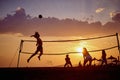 Friends playing volleyball at beach in group, young athletic man jumping hitting ball. Sport, recreation, fun, togetherness, Royalty Free Stock Photo