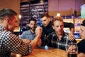 Friends plays arm wrestling. Group of people together indoors in the pub have fun at weekend time Royalty Free Stock Photo