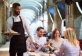 Friends in restaurant and black waiter Royalty Free Stock Photo