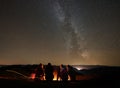 Friends resting beside camp, campfire under night starry sky Royalty Free Stock Photo