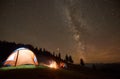 Friends resting beside camp, campfire under night starry sky Royalty Free Stock Photo