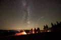 Friends resting beside camp, campfire under night starry sky Royalty Free Stock Photo