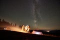 Friends resting beside camp, campfire under night starry sky Royalty Free Stock Photo