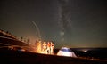 Friends resting beside camp, campfire under night starry sky Royalty Free Stock Photo