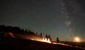 Friends resting beside camp, campfire under night starry sky Royalty Free Stock Photo