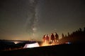 Friends resting beside camp, campfire under night starry sky Royalty Free Stock Photo