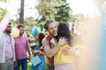 Friends reunite after a long time apart. Men and women embracing, happy to meet at garden party. Royalty Free Stock Photo