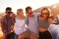 Friends On Road Trip Sitting On Hood Of Convertible Car Royalty Free Stock Photo