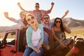 Friends On Road Trip Standing In Convertible Car