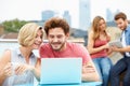 Friends On Roof Terrace Using Laptop And Digital Tablet Royalty Free Stock Photo