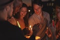 Friends on a rooftop lighting candles on a birthday cake