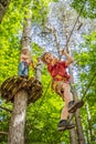 Friends on the ropes course. Young people in safety equipment are obstacles on the road rope