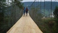 Friends run racing outdoors on mountains bridge. Tourists wear backpacks on hike