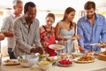 Friends serving themselves food and talking at dinner party