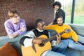 Friends Sharing a Musical Moment with Guitar on a Cozy Couch Royalty Free Stock Photo