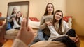 Friends shooting photographs of two beautiful smiling teenage girls at home for social media website. Modern Royalty Free Stock Photo