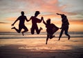 Friends, silhouette and jump on the beach during sunset on vacation together. Excited people on travel holiday in summer Royalty Free Stock Photo