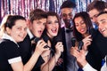 Friends singing into microphones at karaoke party Royalty Free Stock Photo