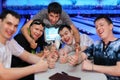 Friends sit at table and thumb up in bowling