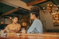 Friends sitting at a bar couner enjoying drinks together Royalty Free Stock Photo