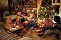 Friends sitting next to a Christmas tree, eating Christmas cookies, drinking cocoa and having fun Royalty Free Stock Photo