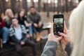 Friends sitting outdoors in the forest. Focus on phone. Royalty Free Stock Photo