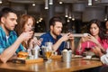 Friends with smartphones dining at restaurant