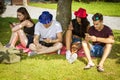 Friends with smartphones under tree