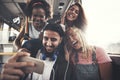 Friends smiling and taking selfies together on a bus