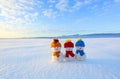 Friends snowman in red, blue, yellow hats and scarfs. Nice winter scenery with mountains, field in snow. Orange sunset background. Royalty Free Stock Photo