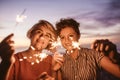 Friends standing on a beach at dusk playing with sparklers Royalty Free Stock Photo