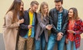 Friends standing by a wall background and using their smarphones - Young people on social media