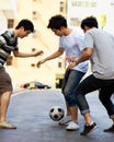 Friends in street playing football together for sports, fun and happy energy with urban games in Korea. Games for kids Royalty Free Stock Photo
