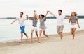 Friends in striped clothes running along beach