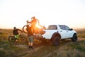 Friends Taking MTB Bikes off the Pickup Offroad Truck in Mountains at Sunset. Adventure and Travel Concept.