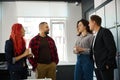 Friends talking during coffee break near luggage lockers in coworking office