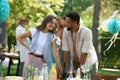 Friends talking, flirting and having fun at summer grill garden party. Multiracial couple hosting garden party. Royalty Free Stock Photo