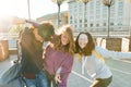 Friends teenagers students with school bags, having fun on the way from school. City background, golden hour