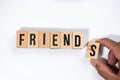 ` FRIENDS ` text made of wooden cube on White background with hand