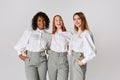 Three fashionable stylish young women in office style clothes standing and smiling over light background. Concept of Royalty Free Stock Photo