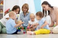 Friends with toddlers playing on the floor in play room Royalty Free Stock Photo