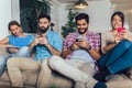 Friends using electronic devices while sitting on sofa Royalty Free Stock Photo