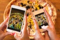 Friends using smartphones to take photos of their pizza