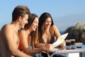 Friends on vacations consulting a guide in an hotel terrace